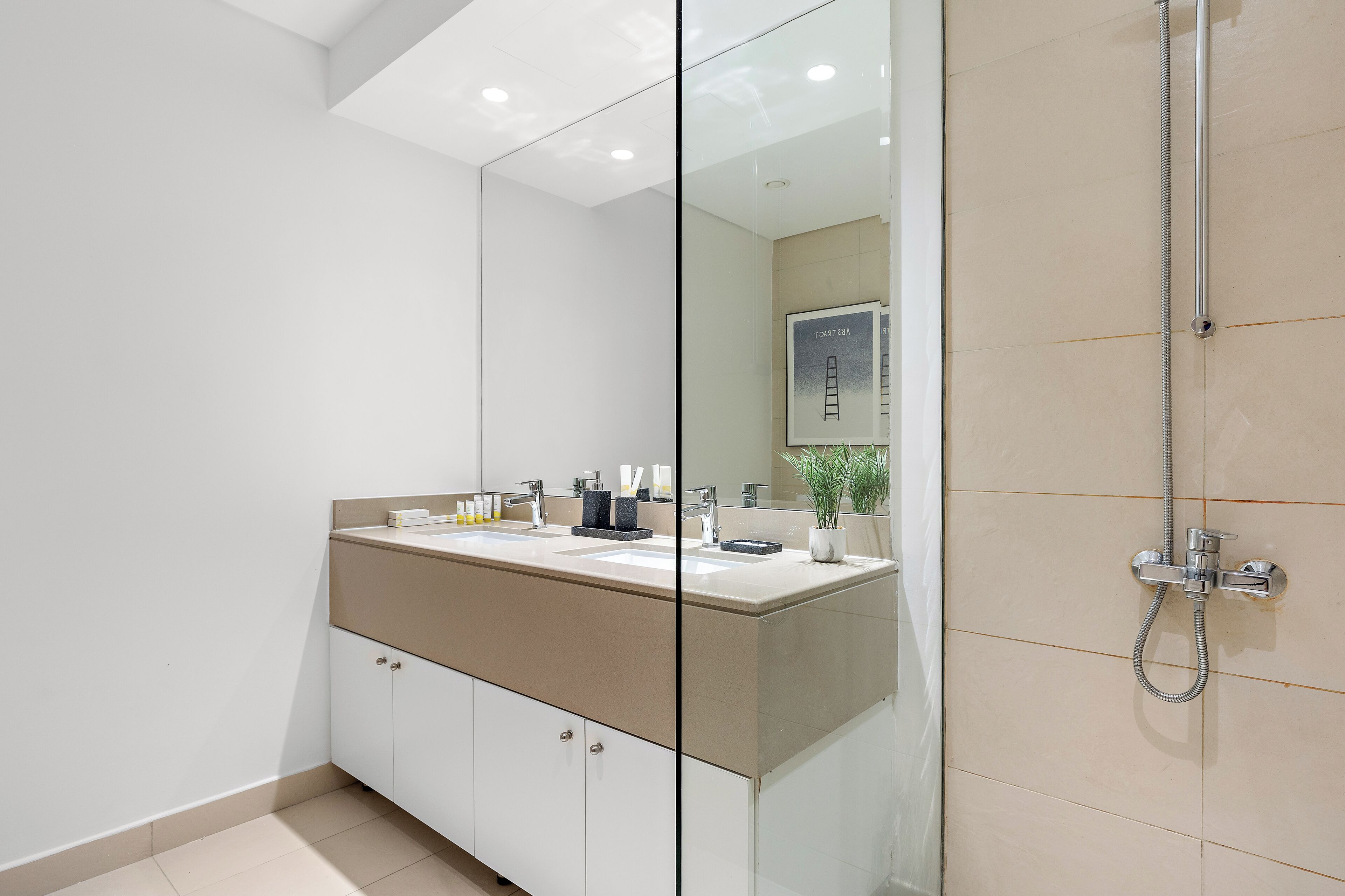 A modern bathroom with a large mirror, a shower, and a vanity with a sink.