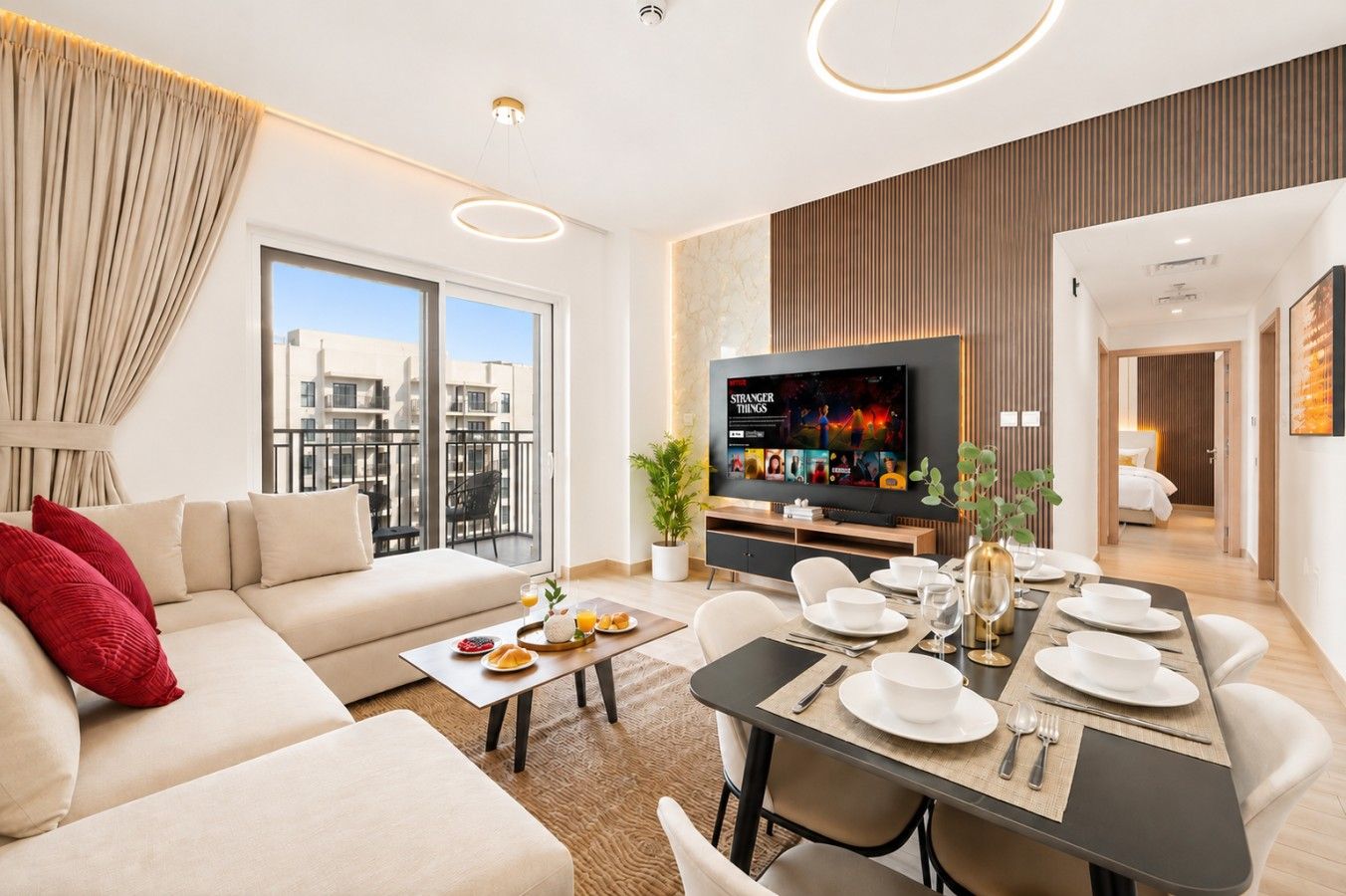 A modern living room with a sofa, dining table, TV, and balcony with city views.