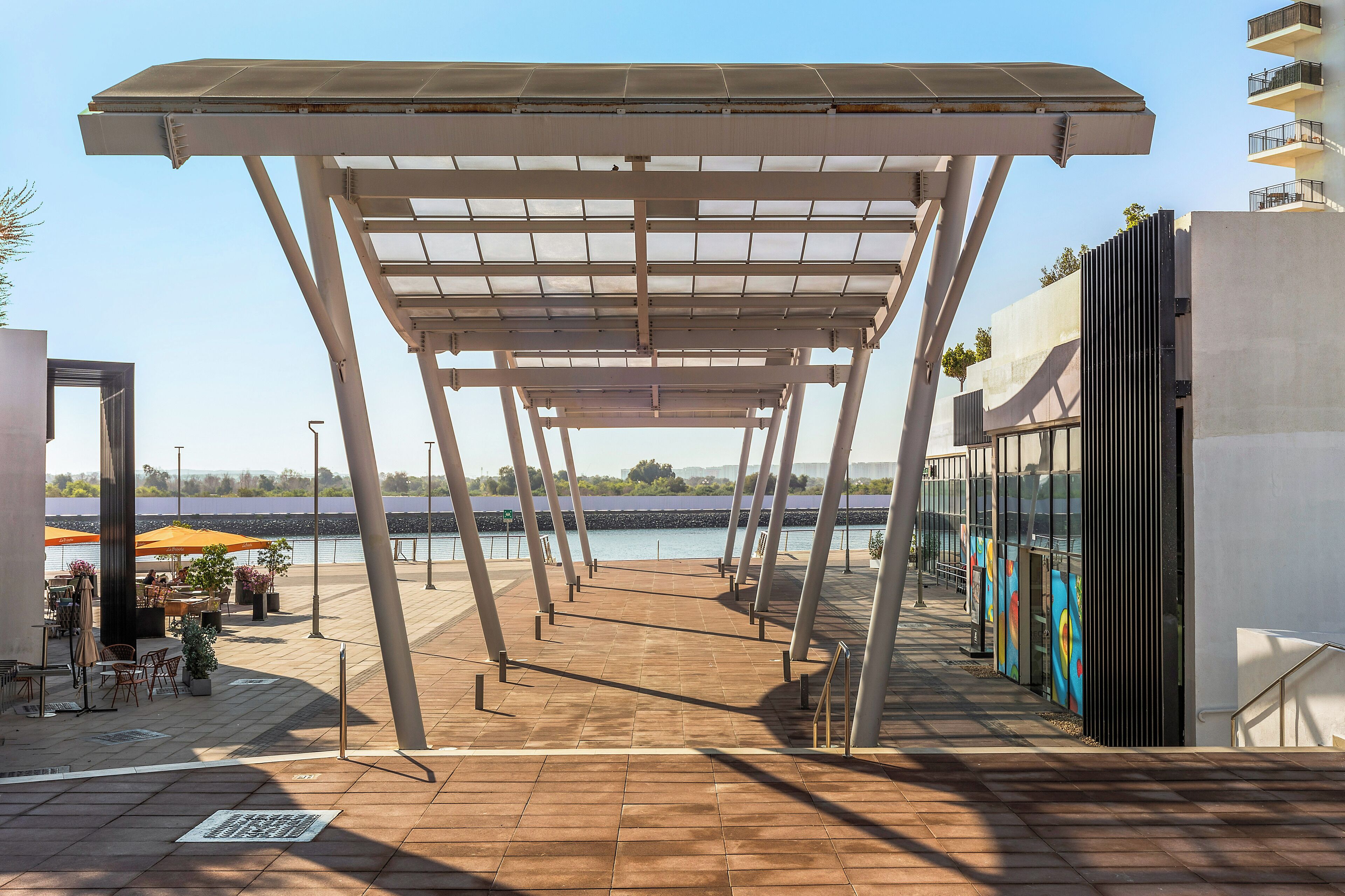 An outdoor terrace with a pergola, seating area, and a view of the water.