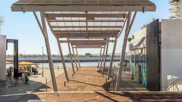 An outdoor terrace with a pergola, seating area, and a view of the water.