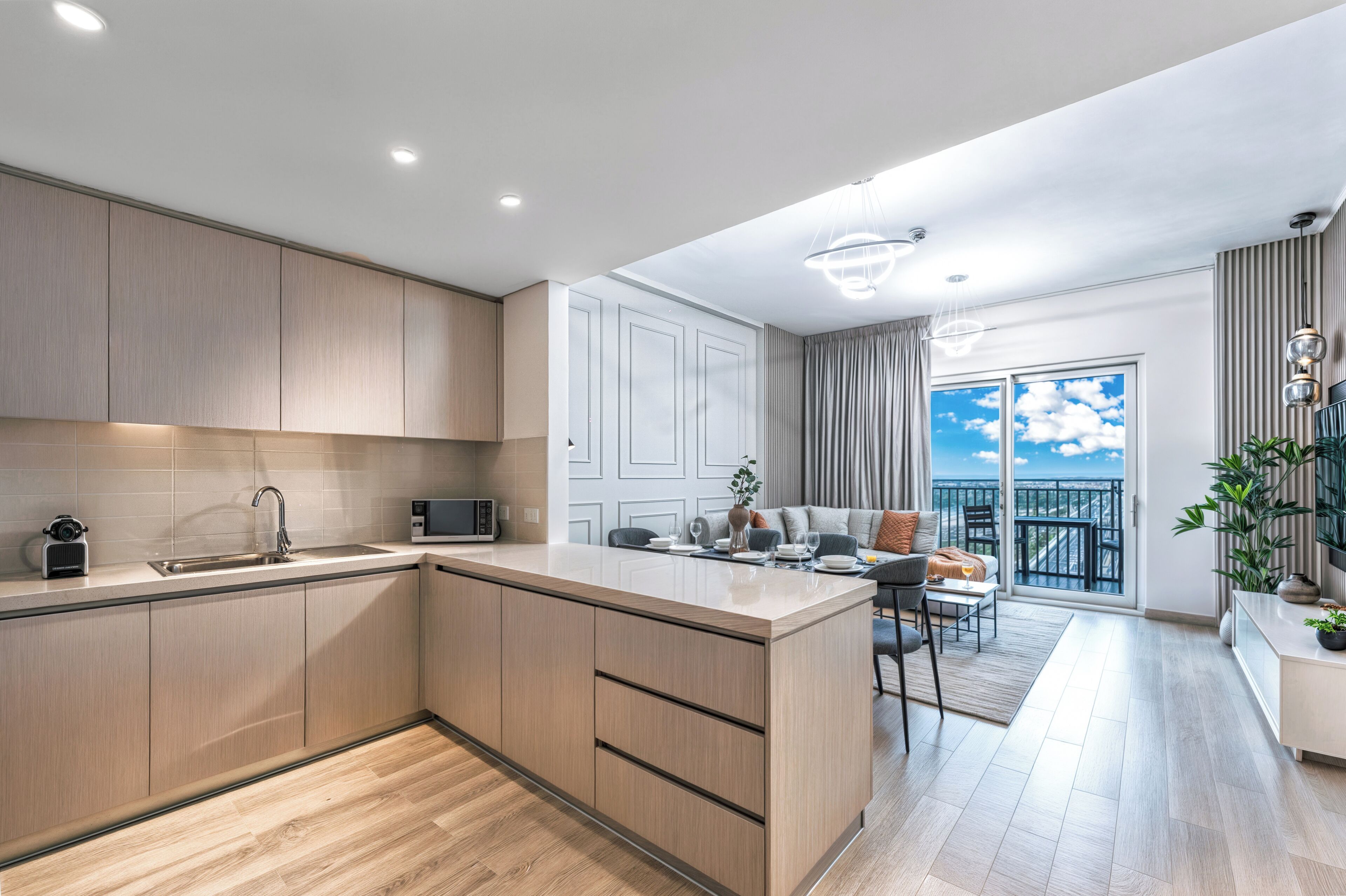 A modern kitchen with a central island, a dining area with a view, and a balcony with a railing.