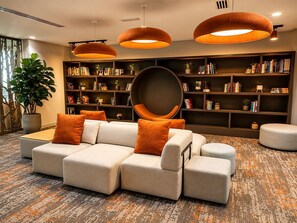 A modern living room with a sectional sofa, multiple bookshelves, and large pendant lights. - Desert Key - Perfectly Located Yas Island Premier Apts (Abu Dhabi)