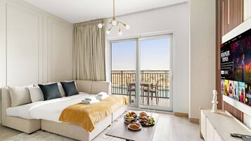 A modern hotel room with a large bed, a balcony with a view, and a television displaying a movie.