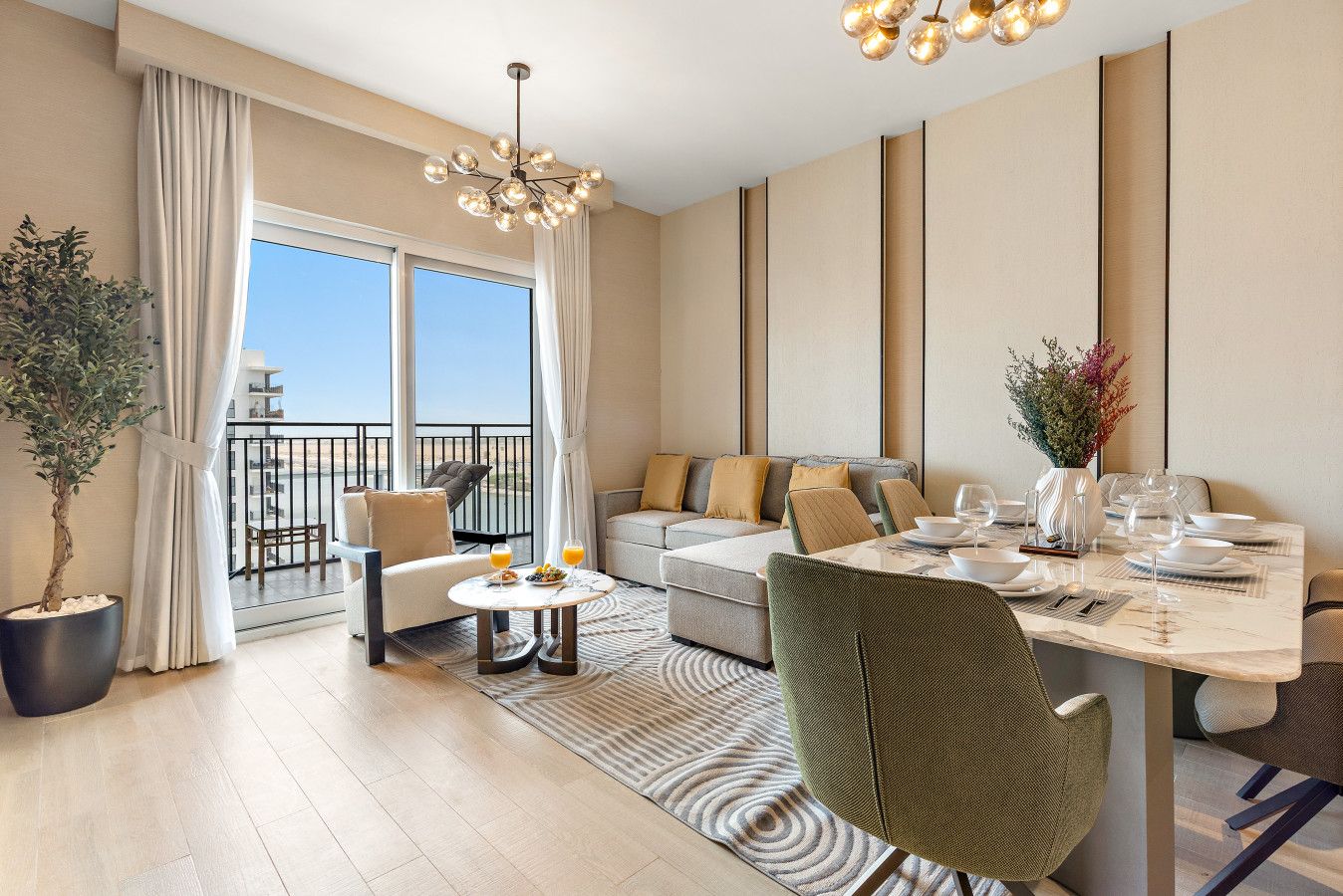 A hotel room with a balcony, a dining area, and a seating area with a sofa and chairs.