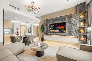 A modern living room with a flat-screen TV, comfortable seating, a dining area, and a kitchen. - Desert Key - Perfectly Located Yas Island Premier Apts (Abu Dhabi)
