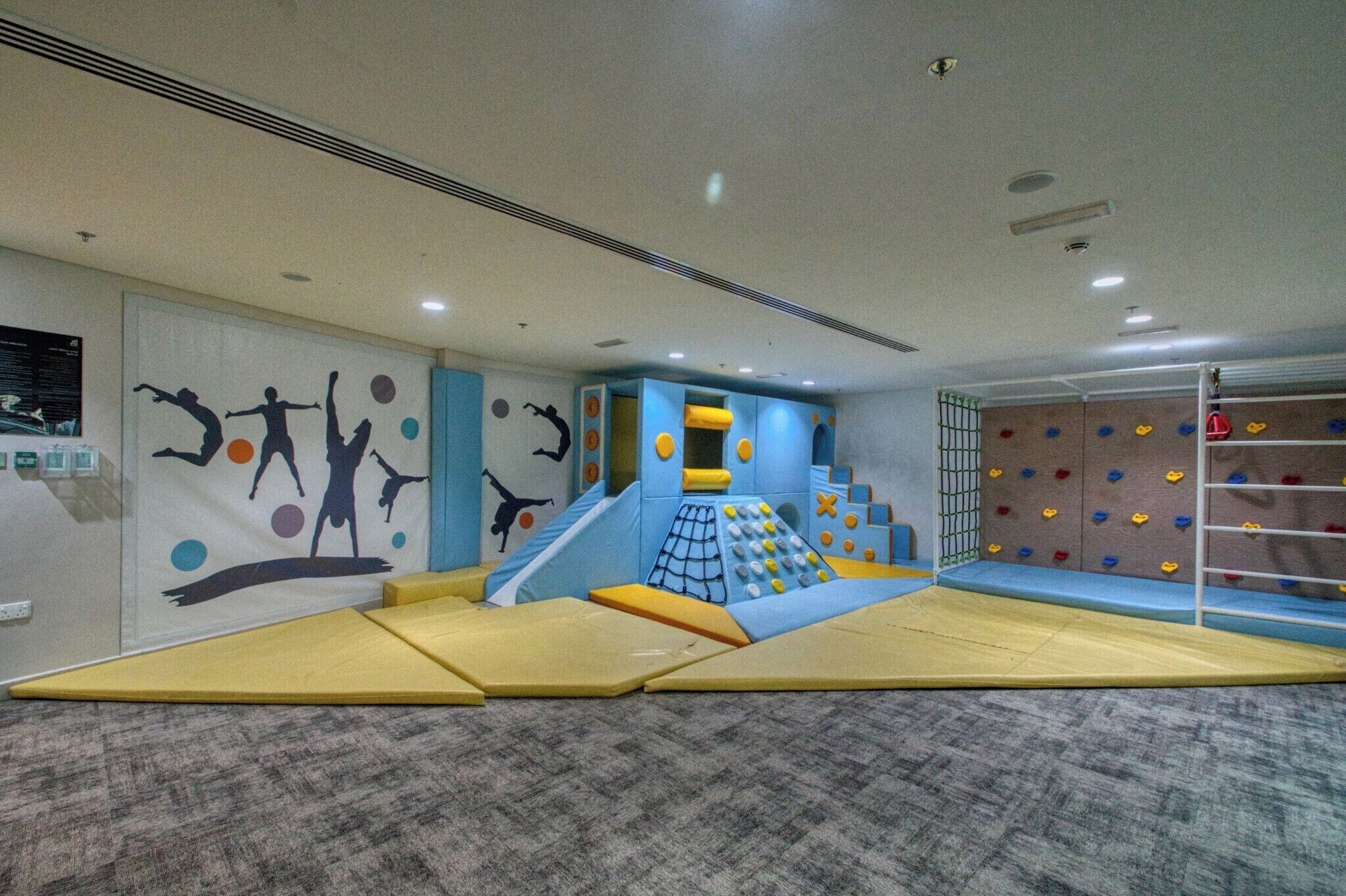 Zona de juegos con muros de escalada y un tobogán.