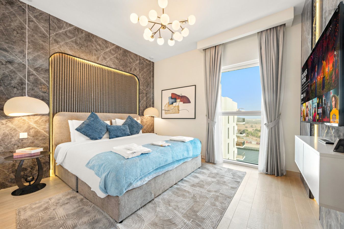 Una habitación de hotel moderna con una cama grande, vistas a la ciudad y un balcón.