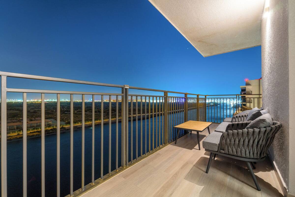 A balcony with a view of a river, a table, and a sofa.