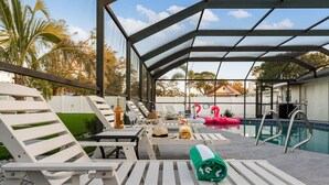 A poolside area with lounge chairs, a pool, and a covered seating area.