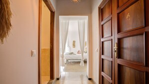 A hallway leading to a bedroom with a bed, a nightstand, and a wall-mounted lamp. - Hotelet Ca'n Oms Mozart by Rentallorca (Petra)