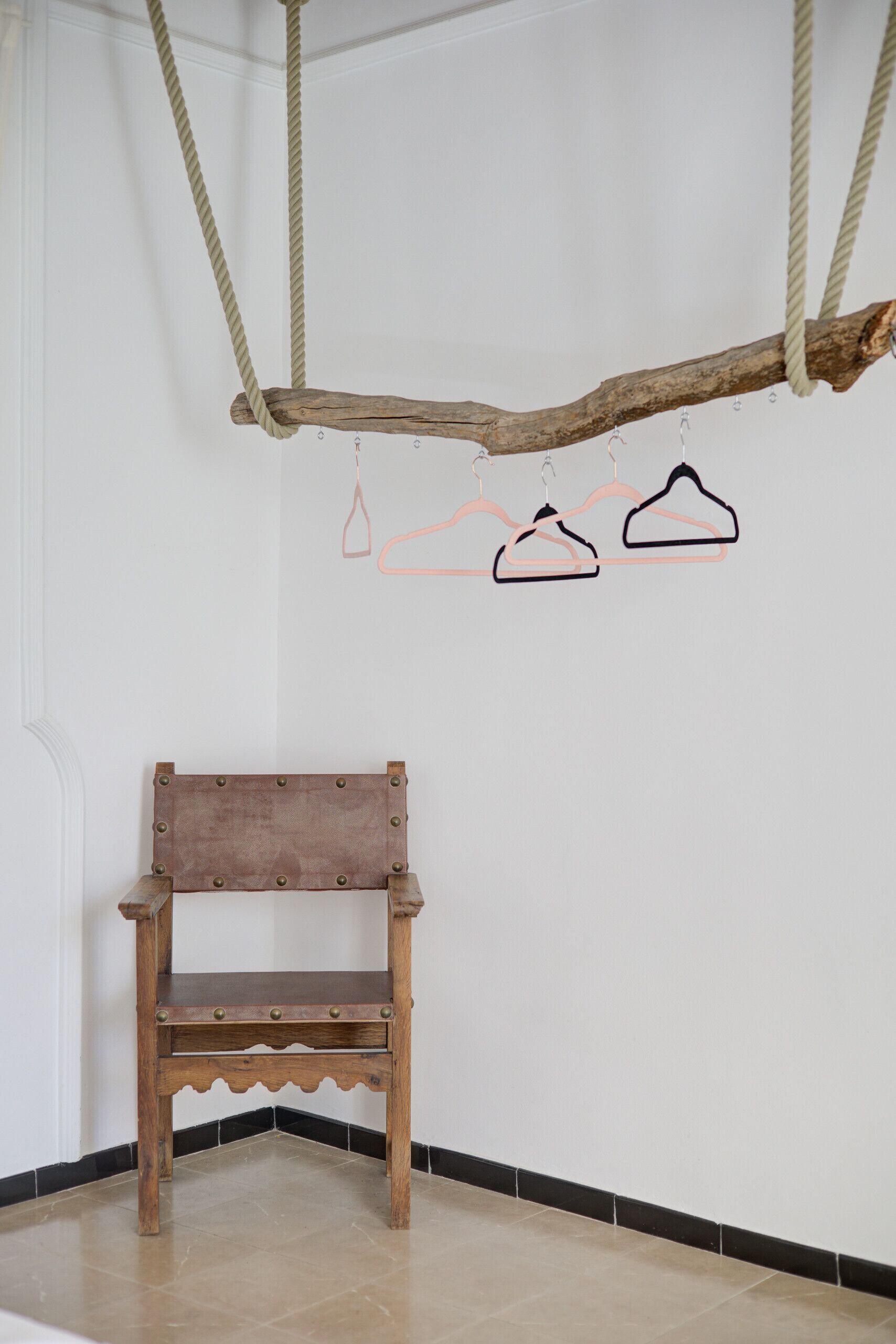 Een houten bankje in een hoek, met een witte muur en een hangende houten balk erboven.