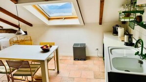 A compact kitchen with a skylight, a dining area with chairs, a trash bin, and a sink with a green faucet. - Hidden gem Al Lago, authentic yet modern 2-bedroom house in medieval hamlet (Colonno)