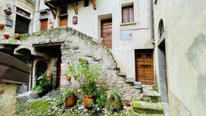 A narrow alleyway with stone walls, wooden doors, and potted plants. - Hidden gem Al Lago, authentic yet modern 2-bedroom house in medieval hamlet (Colonno)