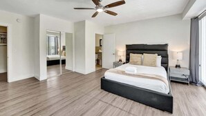 Une chambre moderne avec un grand lit, un ventilateur de plafond et un dressing.