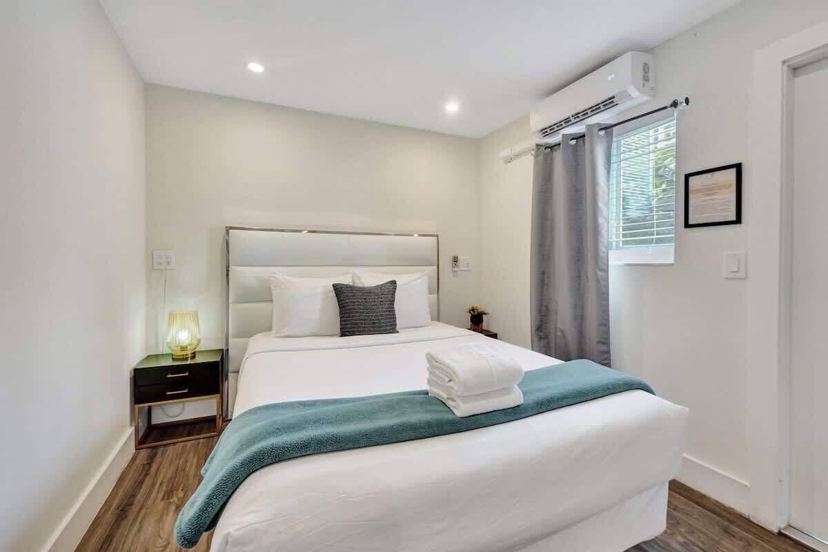 Une chambre d’hôtel moderne avec un grand lit, une table de chevet avec une lampe et une fenêtre avec des rideaux.