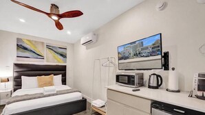 Une chambre d’hôtel moderne équipée d’un lit, d’un bureau avec un micro-ondes, d’une machine à café et d’un téléviseur à écran plat.