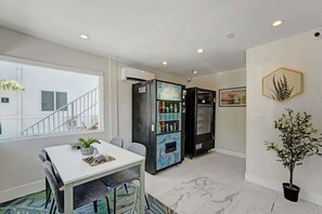 Un intérieur moderne comprenant un coin repas, des distributeurs automatiques, un escalier et une plante en pot.