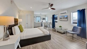 Ein modernes Hotelzimmer mit Bett, Nachttisch, Lampe und Deckenventilator.