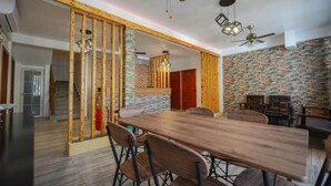 Un comedor moderno con una mesa y sillas de madera, una pared de ladrillo decorativa y ventiladores de techo.
