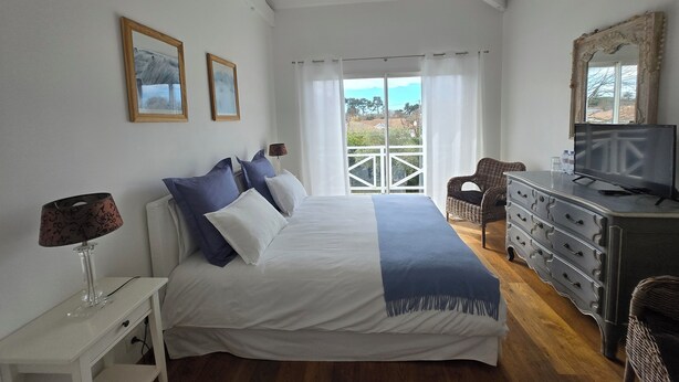 Een slaapkamer met een bed, een kaptafel, een televisie en een balkon met uitzicht.