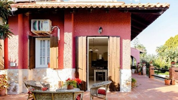 A building with a red facade, a door, and a small patio area with wicker furniture and potted plants. - villa in full relaxation near the sea - air conditioning - wifi (Augusta)