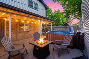 A backyard with a fire pit, outdoor seating, and a hot tub.