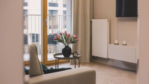 Una sala de estar moderna con un sofá, una mesita con un florero, un mueble aparador y un televisor montado en la pared.