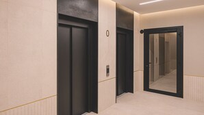 Un ascensor moderno con panel de control, pared espejada y diseño limpio y minimalista.
