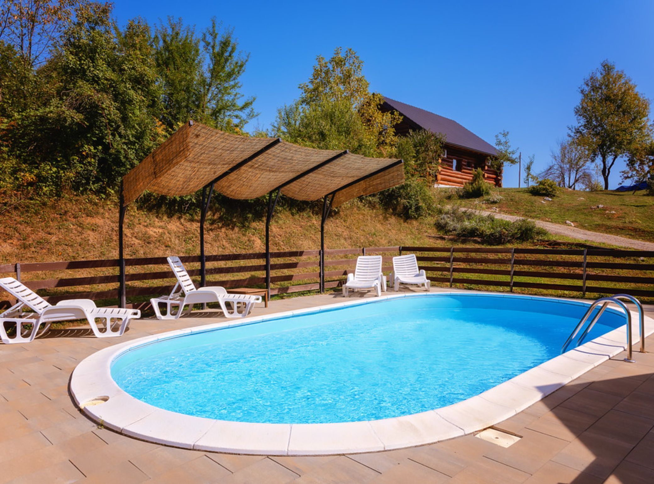 A swimming pool with lounge chairs and a covered area.