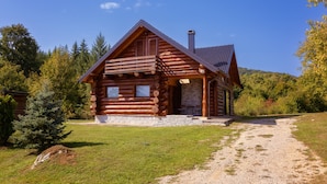 A log cabin with a stone foundation, a chimney, and a porch with a stone bench. - Holiday Home Elizabeta (Slunj)