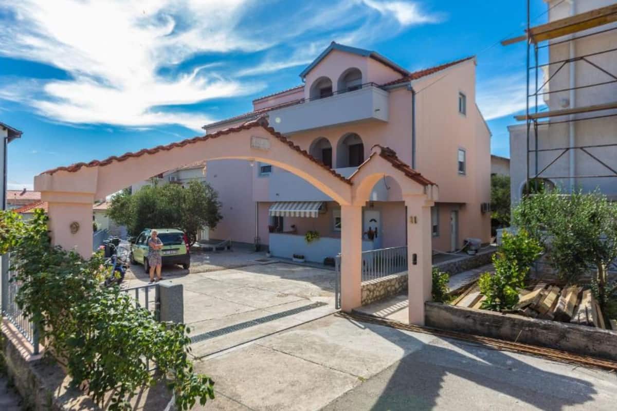 Um edifício de dois andares com fachada rosa e telhado em azulejos.