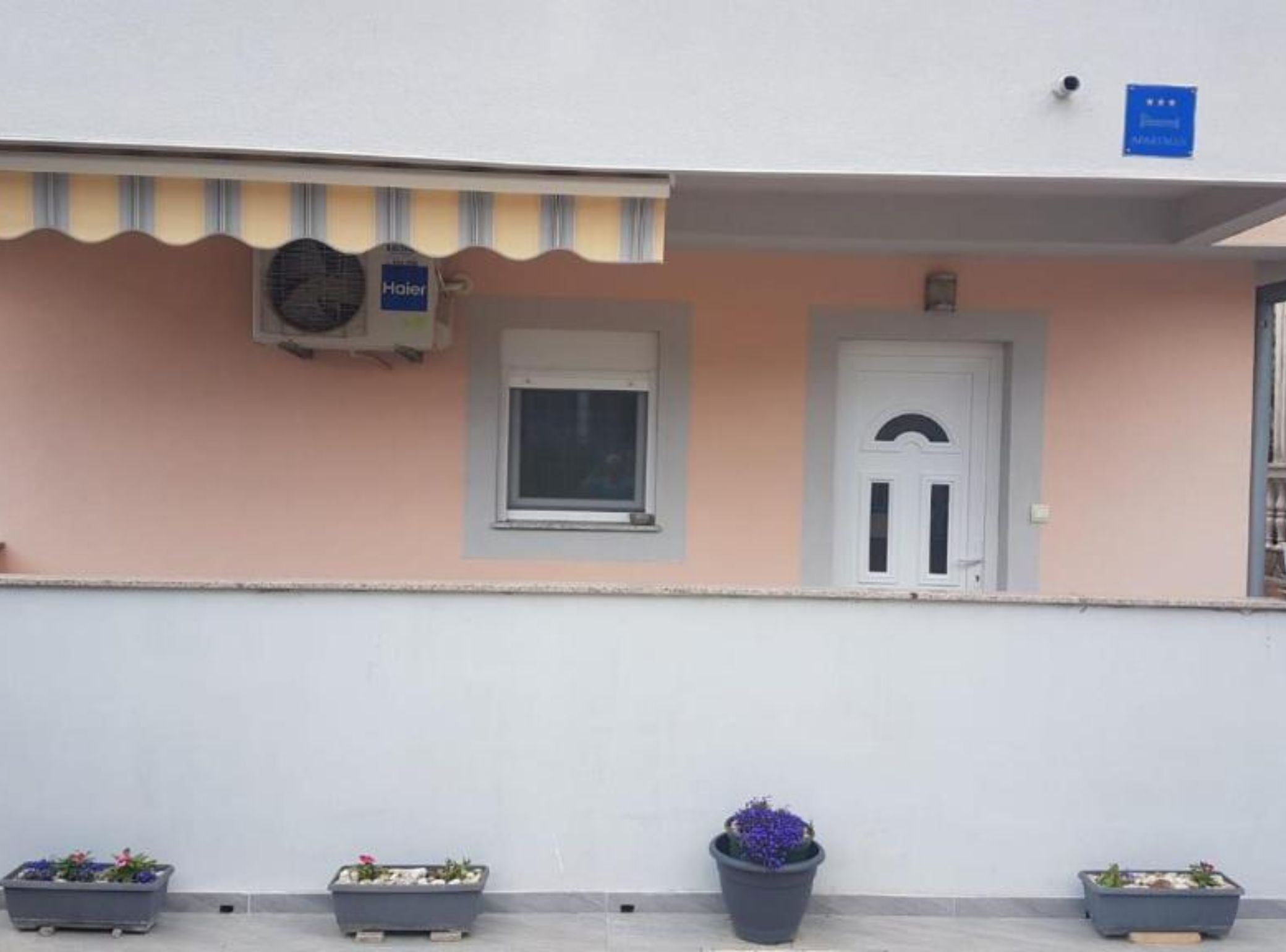 A building facade with a small window, a door, and a sign indicating a room type.