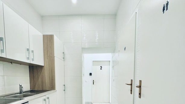 A modern kitchen with white cabinets, a marble floor, and a door marked with the number 2. - 5BR Apartment Near Kaufpark Alterlaa (Vienna)