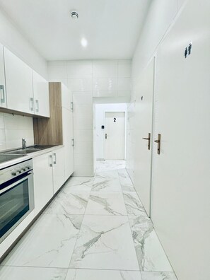 Una cocina moderna con armarios blancos, piso de mármol y una puerta con el número 2.