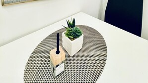 A modern room with a large mirror, a round table with a potted plant, and a black chair. - 5BR Apartment Near Kaufpark Alterlaa (Vienna)