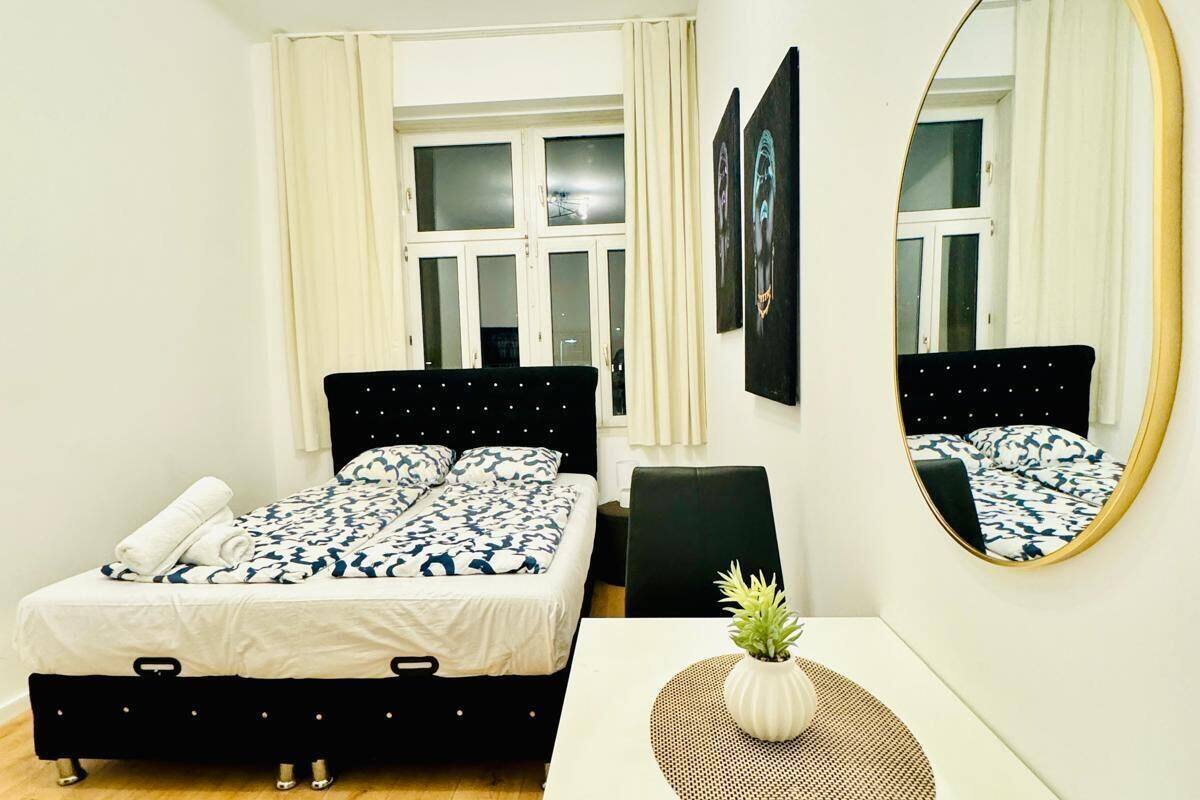 Une chambre à coucher avec un lit, un bureau, une chaise, un miroir et une fenêtre.