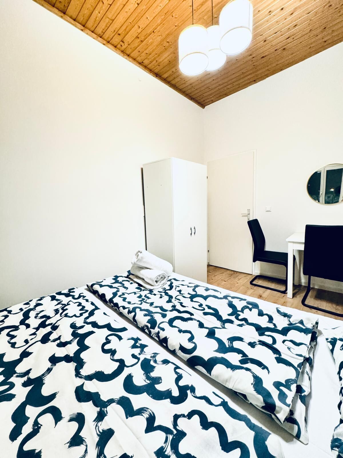 Um quarto com cama, escrivaninha, cadeira e guarda-roupa.