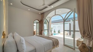 A modern bedroom with a large bed, a ceiling fan, and a view of a pool and outdoor area. - Villa Halle (Cemagi)