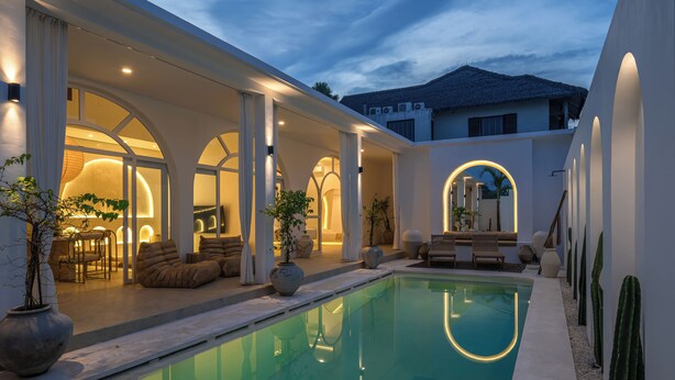 A modern outdoor pool area with a covered seating area, potted plants, and a clear pool. - Villa Halle (Cemagi)