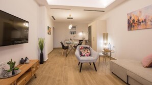 A modern living room with a flat-screen TV, a sofa, a dining area with a table and chairs, and a kitchen in the background. - Sea n City  (Zakynthos)