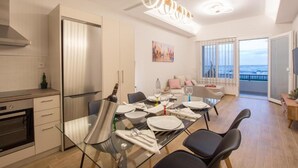 A modern kitchen with a stainless steel refrigerator, a dining table set for four, and a large window offering a view of the sea. - Sea n City  (Zakynthos)