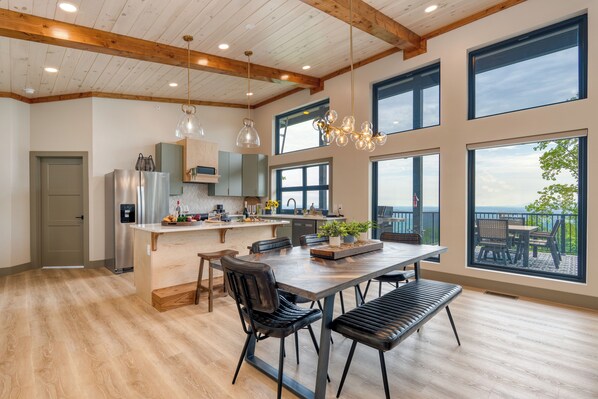 Una cocina amplia con una isla grande, vigas de techo de madera y ventanas que ofrecen vistas al exterior.