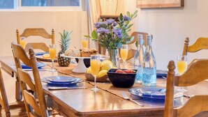 Een eettafel gedekt met borden, glazen, een vaas met bloemen en diverse etenswaren.