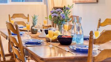 Une table à manger dressée avec des assiettes, des verres, un vase de fleurs et divers aliments.
