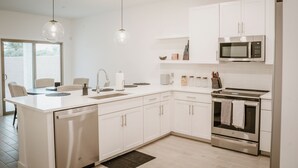 Una cocina moderna con armarios blancos, estufa de acero inoxidable y microondas.
