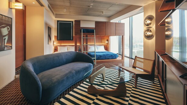 A modern hotel room with a bunk bed, a blue sofa, a glass coffee table, and a checkered floor. - illi Amu Shimokitazawa (Tokyo)