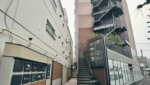 A narrow urban street with a staircase leading to a building with multiple floors. - illi Amu Shimokitazawa (Tokyo)