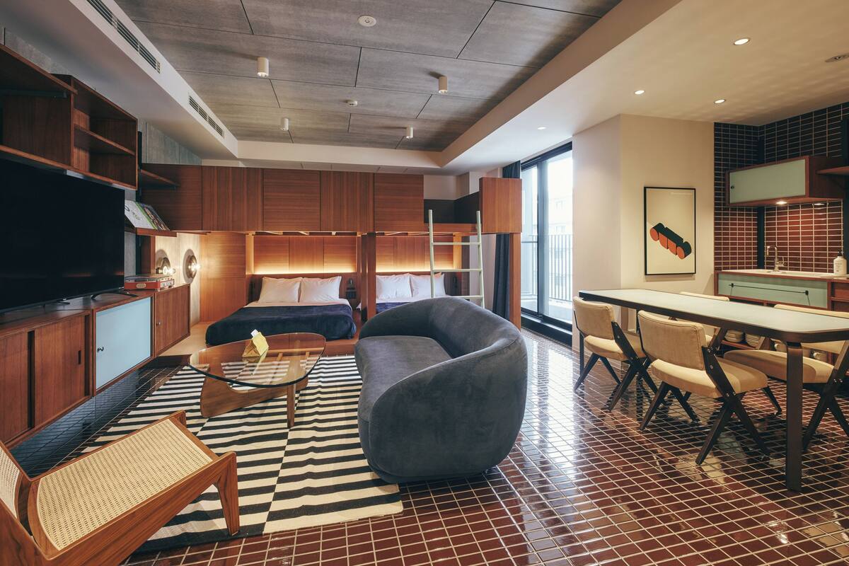 Una habitación de hotel moderna con una cama grande, un sofá, una mesa de comedor y un televisor.