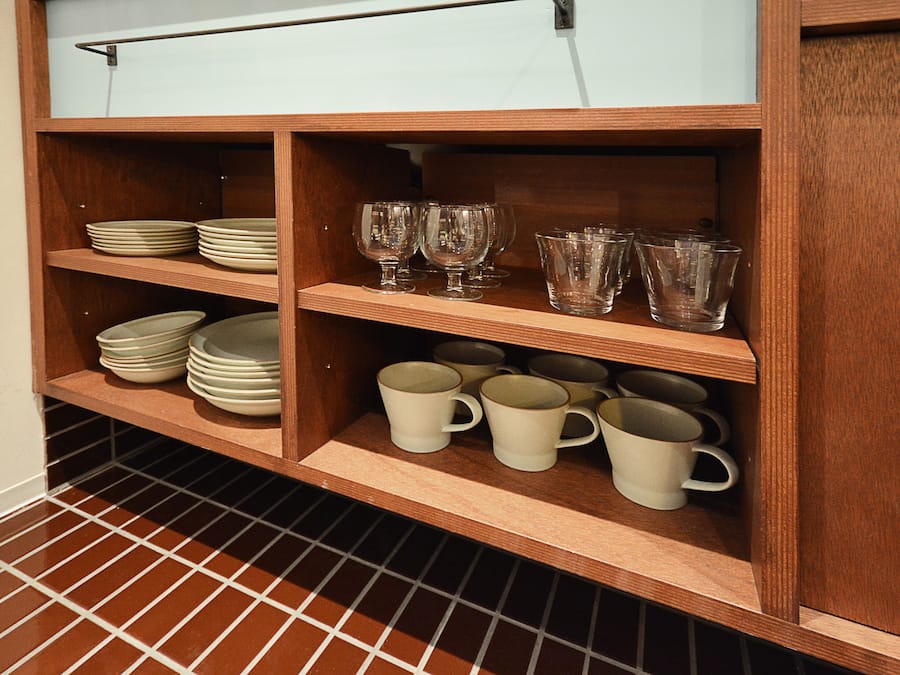 Une étagère en bois, dotée de plusieurs compartiments pour ranger des assiettes, des verres et des tasses.