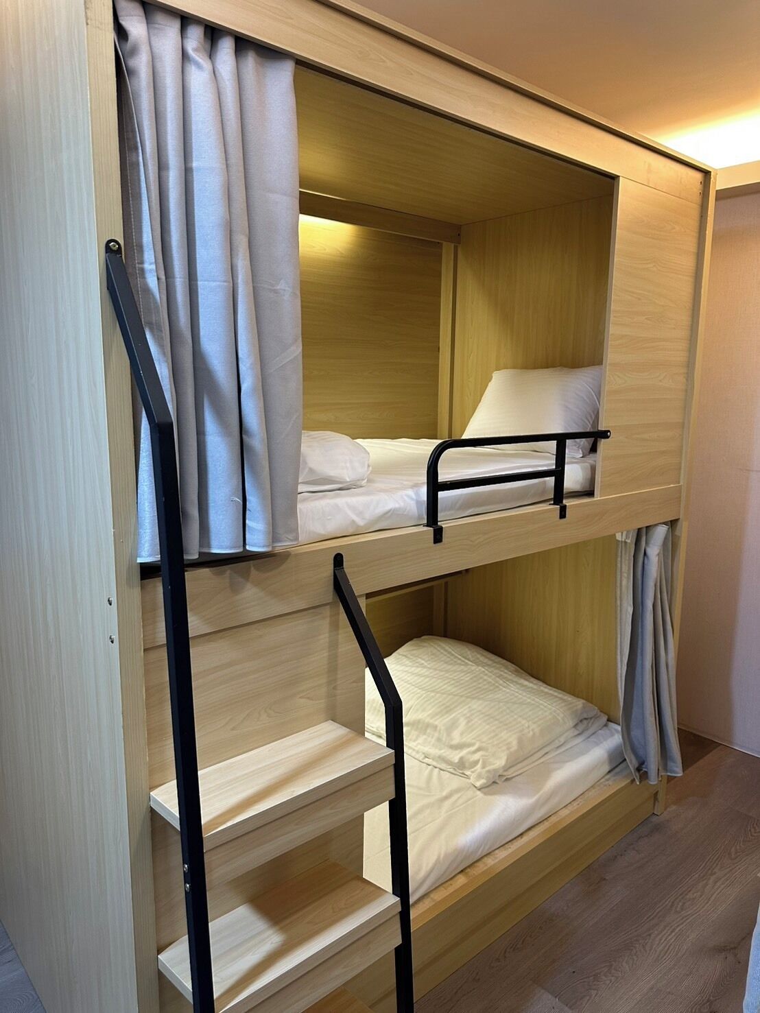 Un lit superposé avec une structure en bois et un lit simple en haut.